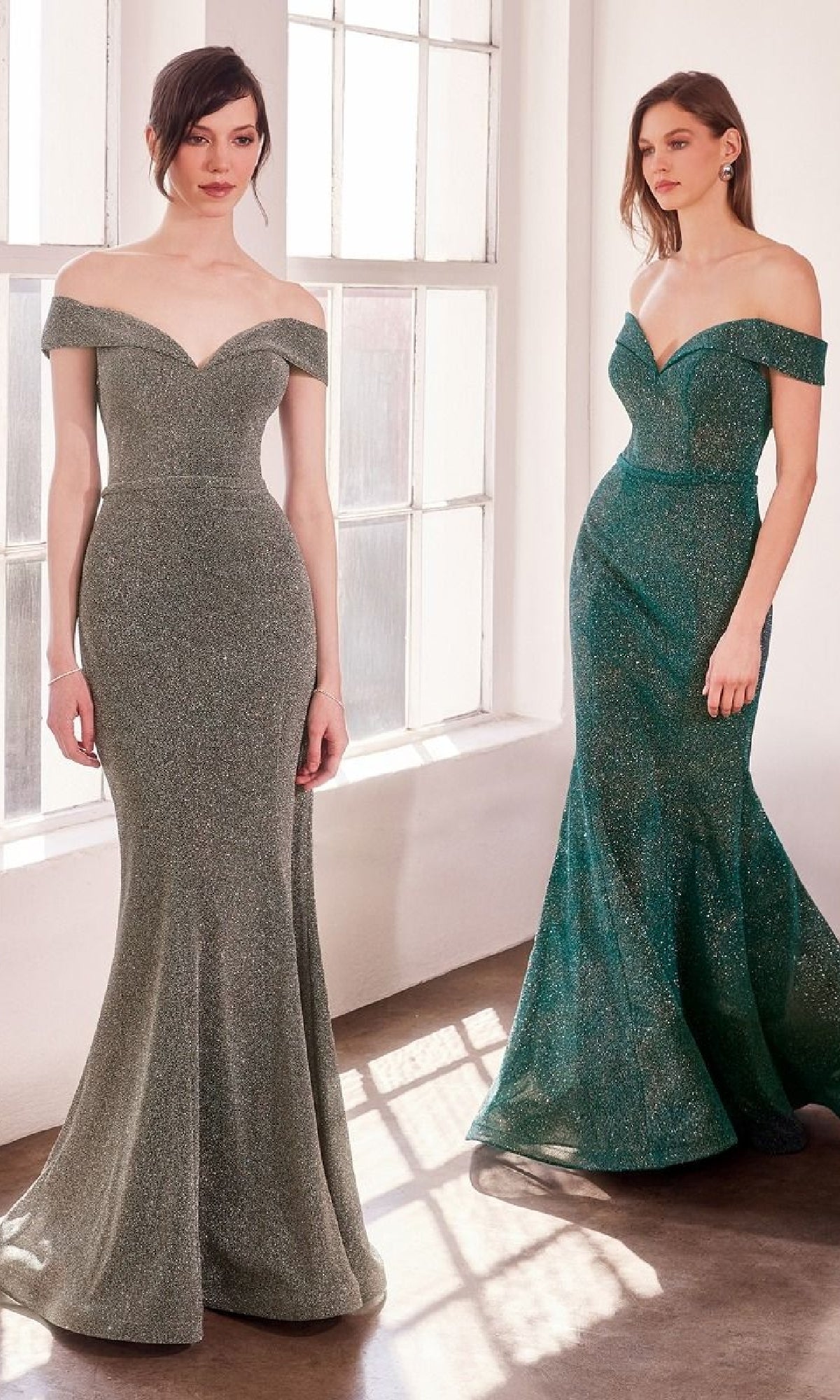 Two women wearing Amoris T602 Off-Shoulder Sweetheart Prom Gowns stand by large windows, their shimmering green dresses glowing in the sunlight.